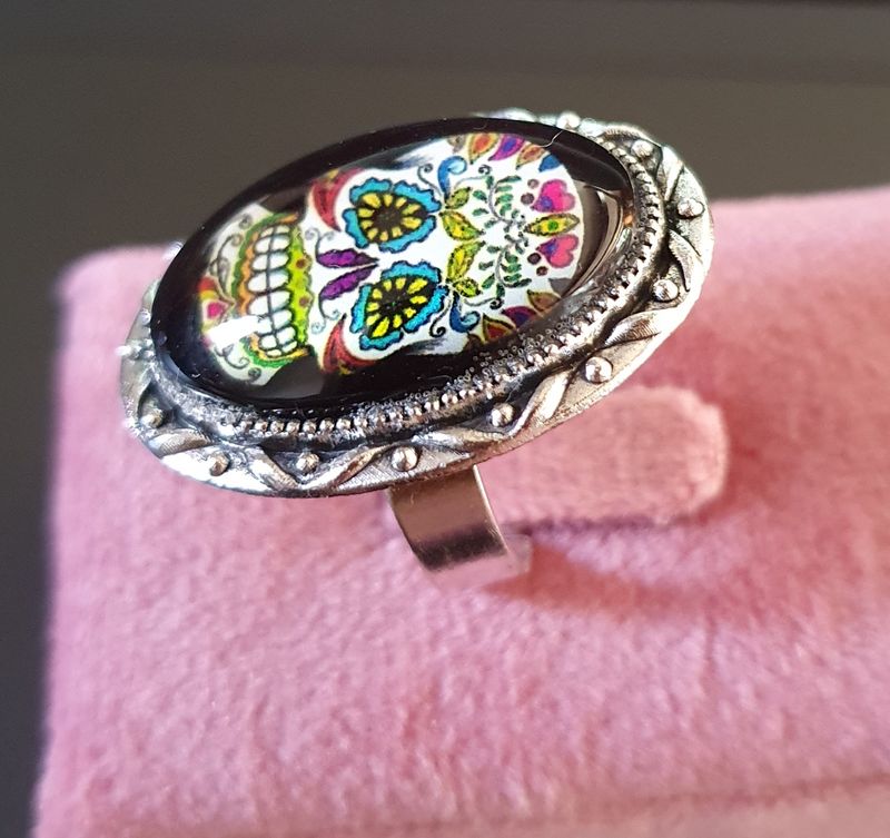 💗 COLLECTION CALAVERAS 💗Bague ovale ajustable en acier inoxydable. Cabochon bombé ovale en verre. Motif Tête de mort multicolore, symbole de la culture Mexicaine. Modèle unique