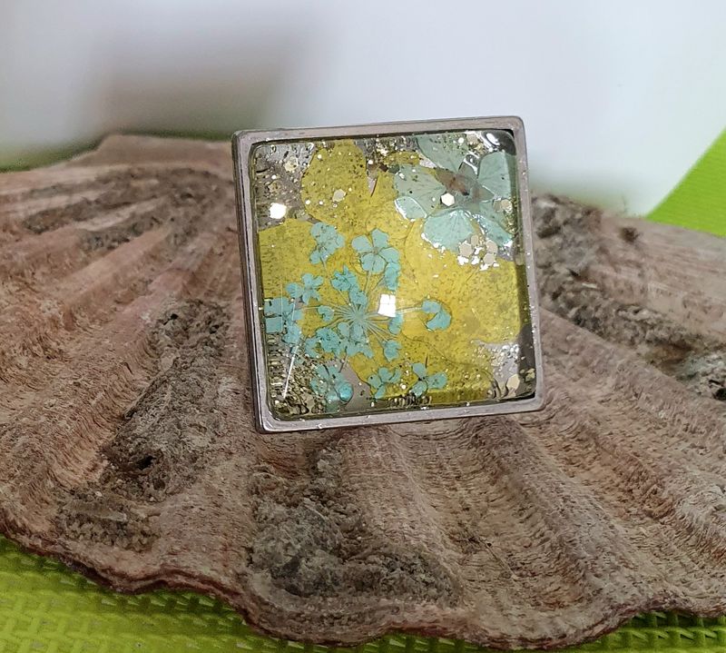 🌼 Bague carrée ajustable en acier inoxydable. Cabochon bombé en verre. Véritables petites fleurs sechées turquoises/jaunes et paillettes. Création artisanale. Modèle unique