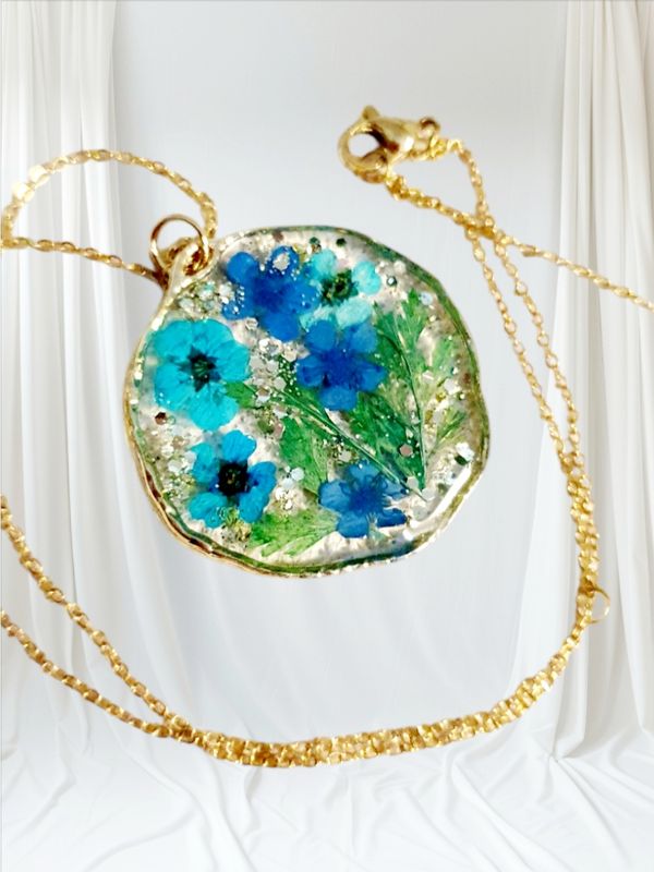 💙 Bucolique 💙 Collier en acier doré inoxydable. Pendentif rond baroque. Résine transparente,  véritables petites fleurs sechées bleues et fougères. Création artisanale. Exemplaire unique.