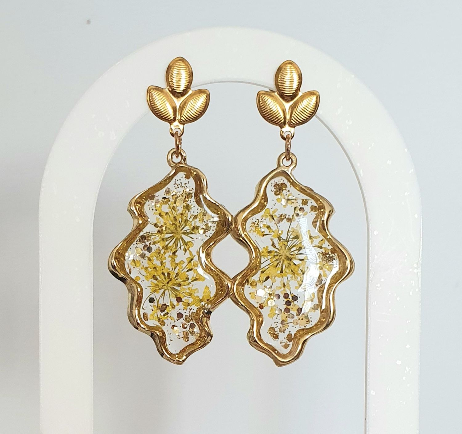 🌿 Boucles d&#39;oreilles feuilles 🍃  en acier doré inoxydable. Résine et petites fleurs de carottes jaunes 🌼🌼 Poudre d&#39;or pailletée. Création artisanale. Exemplaire unique.