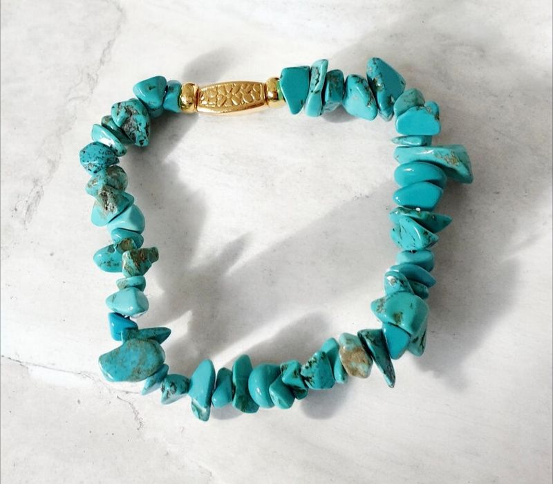 Bracelet extensible T.standard 18,5cm. Chips baroques en pierre reconstituée teintée turquoise. Perle cache-noeud rectangulaire impression fleurs. Création artisanale. Modèle unique.