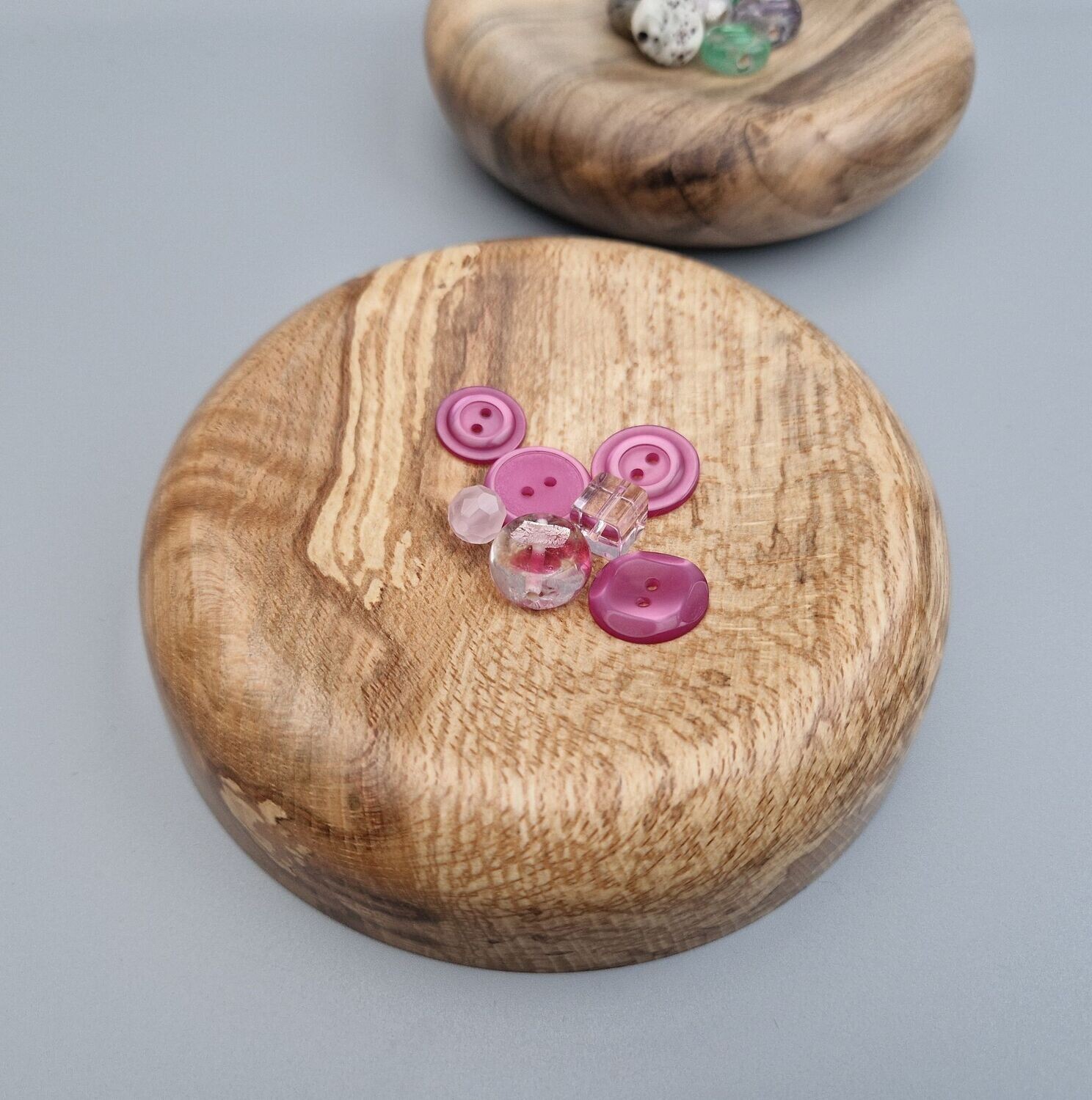 Spalted beech trinket dish with straight sides and gently concaved surface holding some pink buttons and beads. Striking grain pattern.