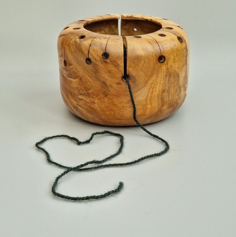 Wooden yarn bowl for knitting or crocheting. The functional holes of the yarn bowl have been incorporated into a design inspired by the Atomic Age graphics of the 1950's. Hand turned from a highly figured piece of spalted beech. Pyrography has been used to apply the minimal graphic decoration.