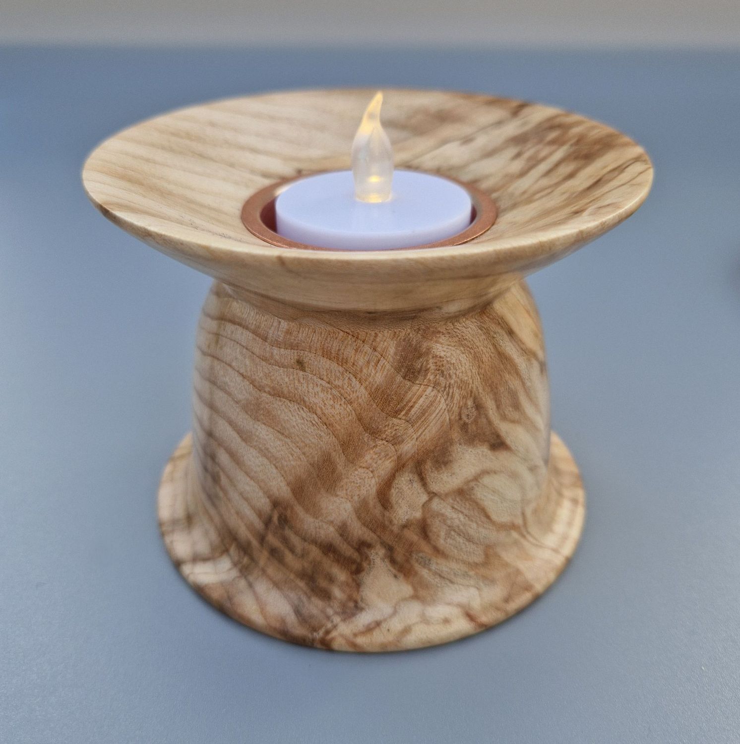 Wide-rimmed tealight holder in spalted sycamore with copper insert; warm tones and soft sheen.