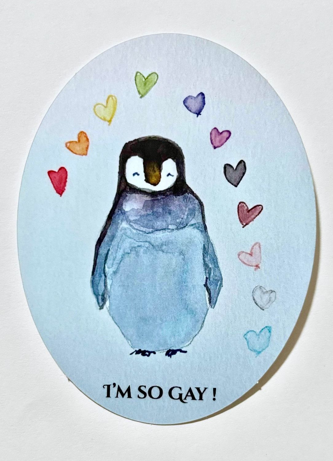 Queer Pride Hand Painted Watercolor Sticker Featuring a Penguin and Rainbow Hearts in Blue and Rainbow Gay Pride Colors