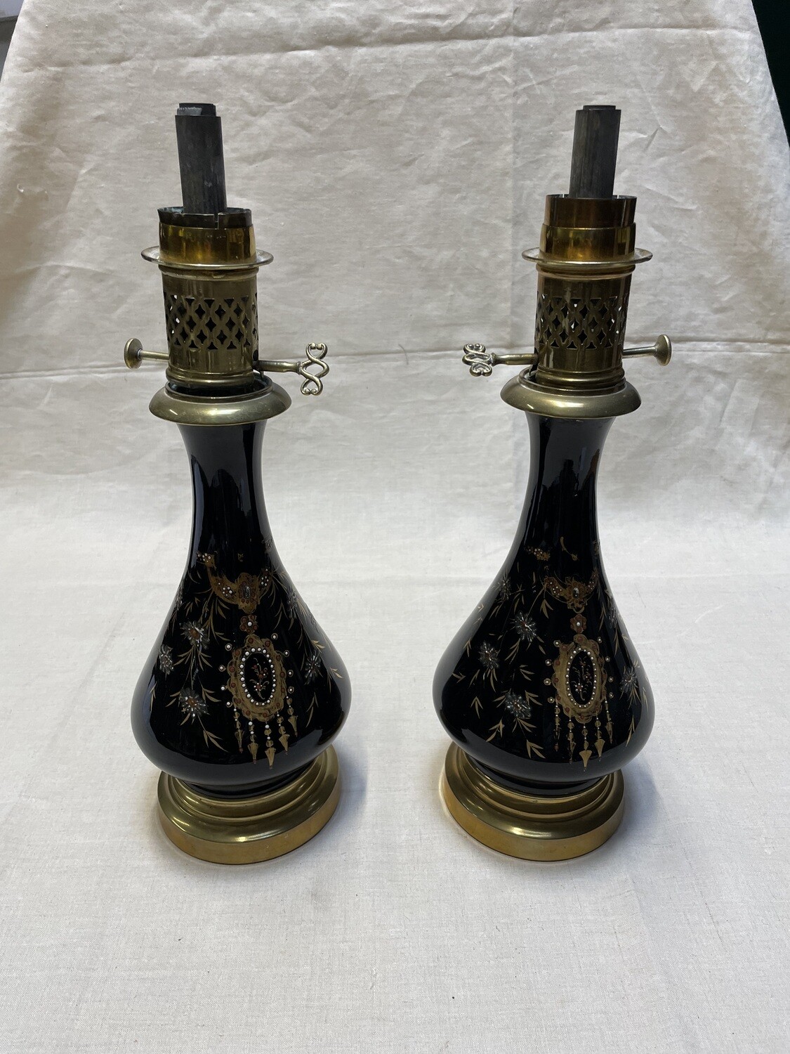 Paire de lampes à huile en porcelaine, réserves en porcelaine bleu intense à rehauts d'émail : motifs végétaux en chute entourant un médaillon, monture laiton, verre, hauteur jusqu'à ladouille: 35.5 c