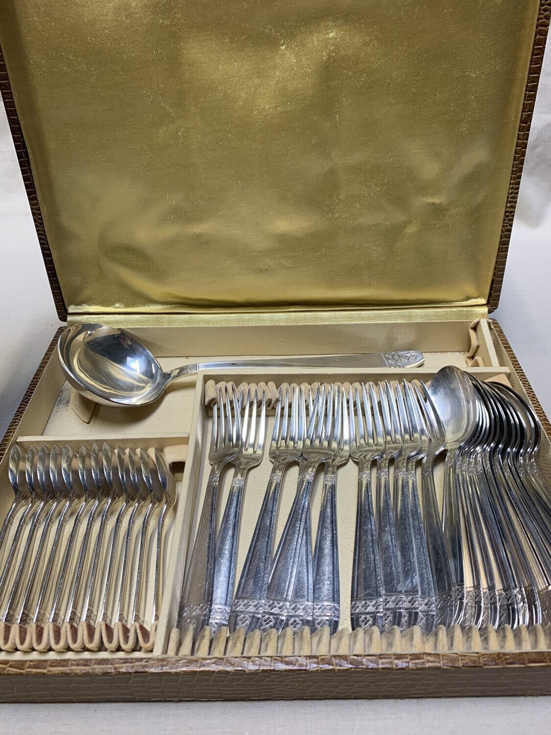 Ménagère en métal argenté dans son écrin comprenant 10 cuillères, 10 fourchettes, une louche