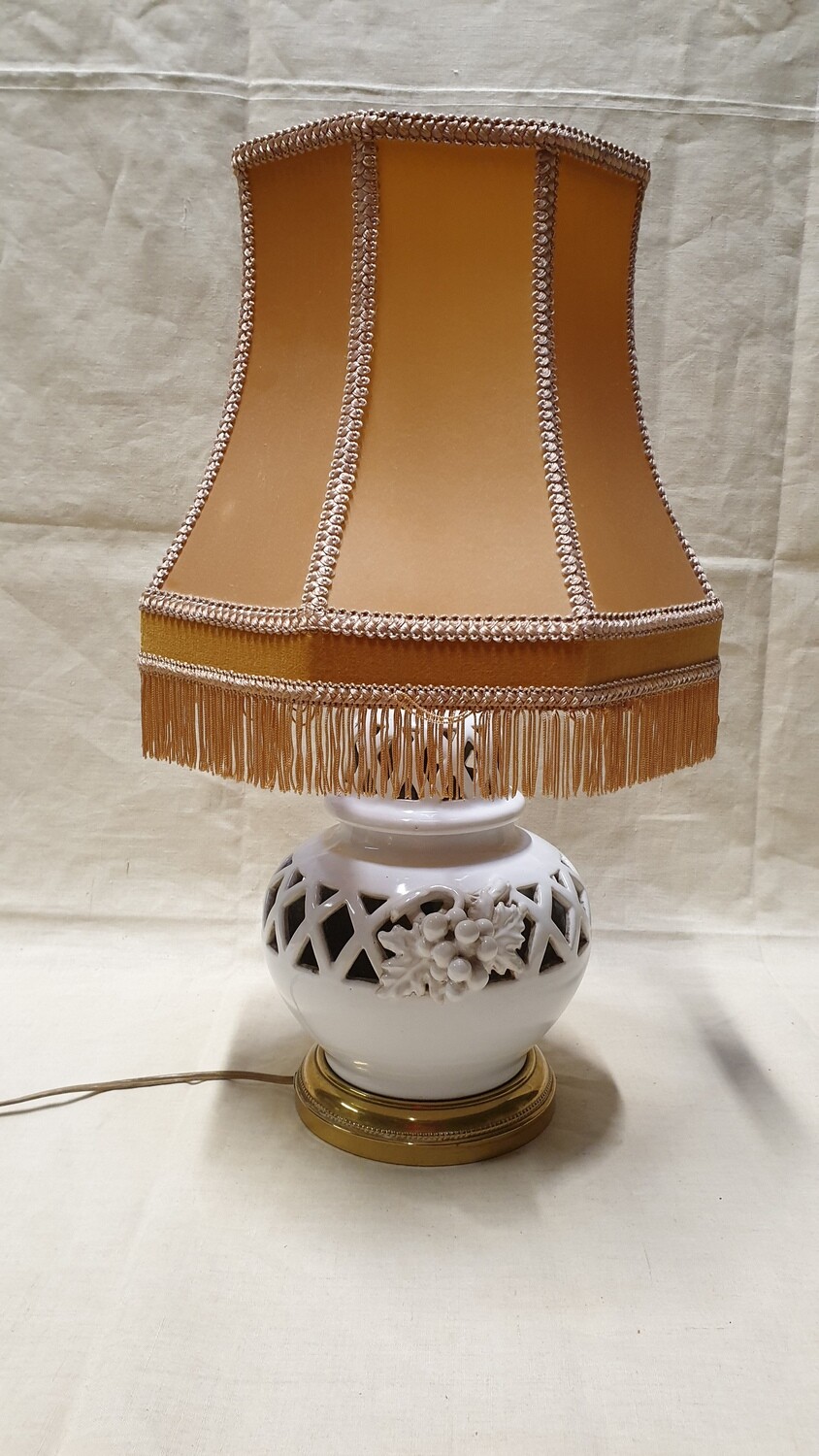 Lampe en faïence émaillée blanche, ajourée, et ornée de pampres, la monture est en métal doré. H-24cm