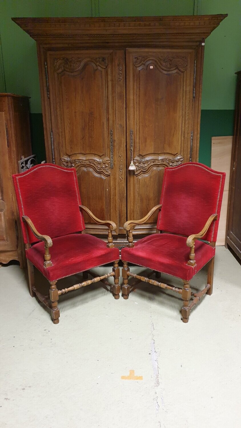 Paire de fauteuils à décor de feuilles d'acanthe et piètement balustre, garniture de velours rouge cloutée