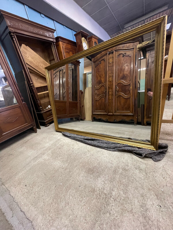 Une grande glace à cadre bois doré de facture récente. Dimensions avec cadre : 130x180 cm