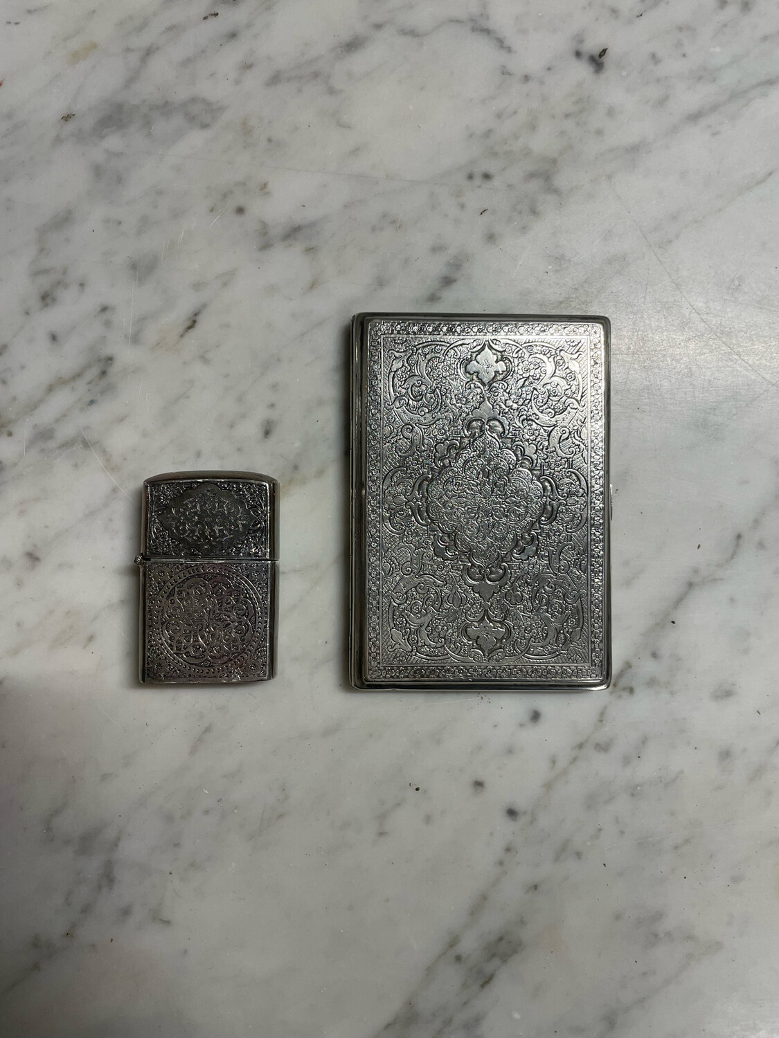 Lot d'un étui à cigarettes et d'un Zippo en métal argenté à décor ciselé