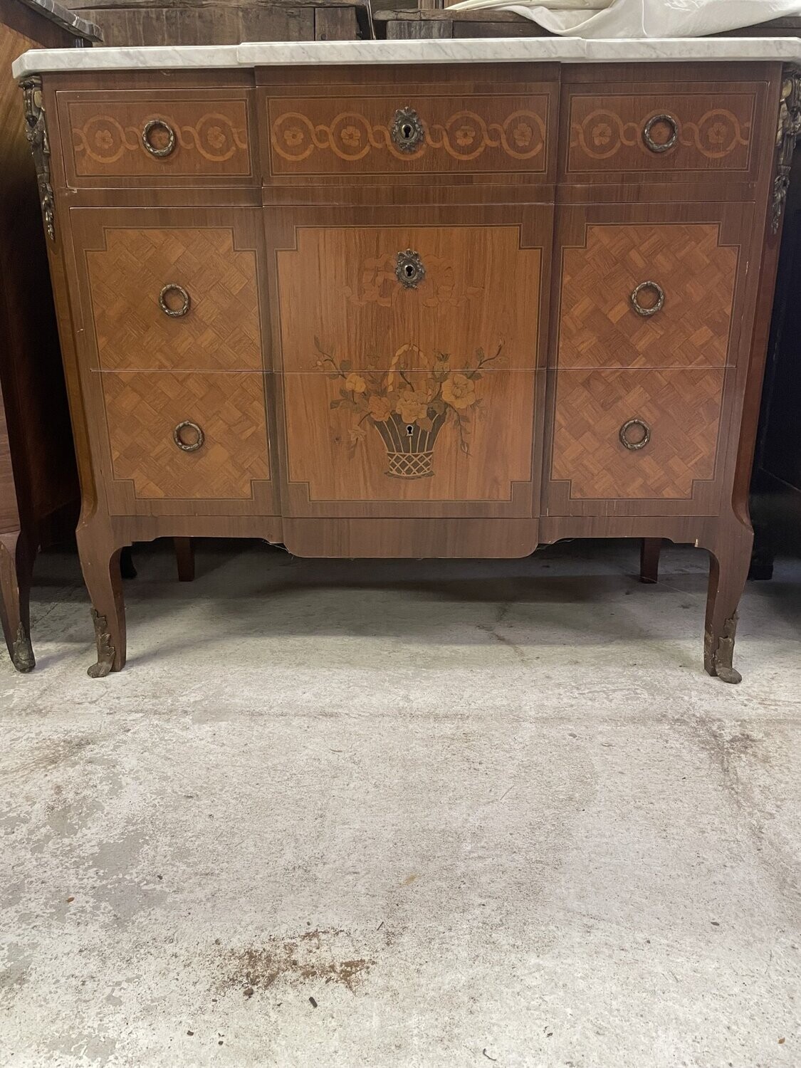 Commode à ressaut central , ouvrant par trois tiroirs, décor marqueté d'un panier fleuri, dessus de marbre blanc à gorge, style Transition. 93 x 110.5 x 51