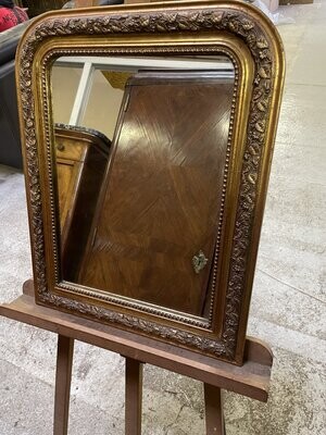 Miroir en bois doré à décor de motifs feuillagés et rangs de perles. 61 x 49 cm.