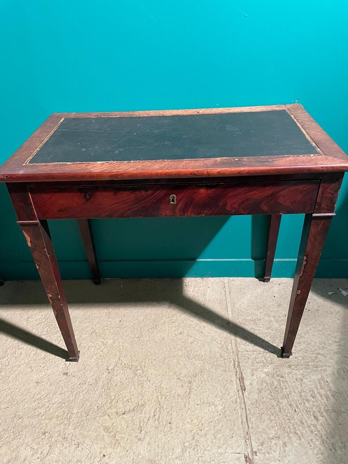 Petit bureau plat, placage d'acajou, un tiroir en ceinture reposant sur des 
pieds gaines à sabots de bronze, début XIXè s. Dim : 73,5 x 80 x 46 cm