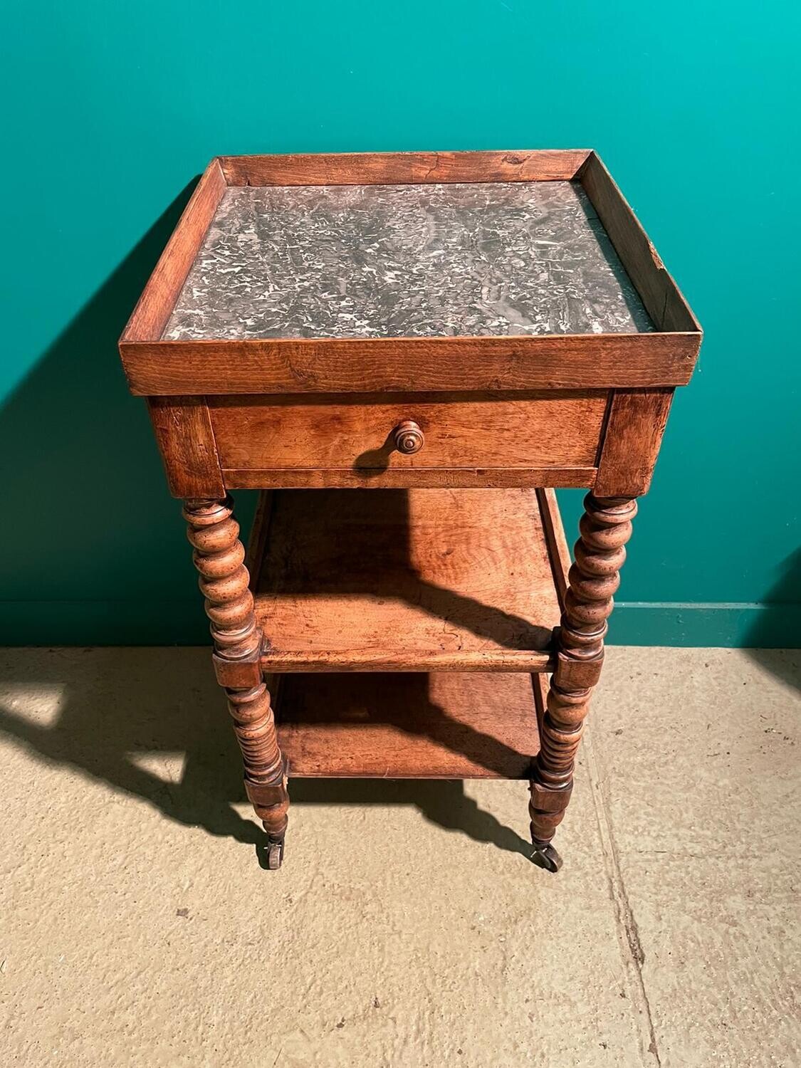 Table d’appoint à roulettes en noyer, à deux tablettes d’entrejambe et plateau de marbre gris veiné. Montants en grains de chapelet. XIXème siècle. H_81 cm L_42 cm