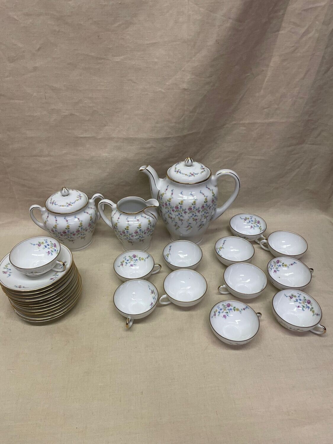 Service à thé en porcelaine à décor floral polychrome et filet or : 12 tasses et sous tasses, une verseuse, un sucrier et un pot à lait