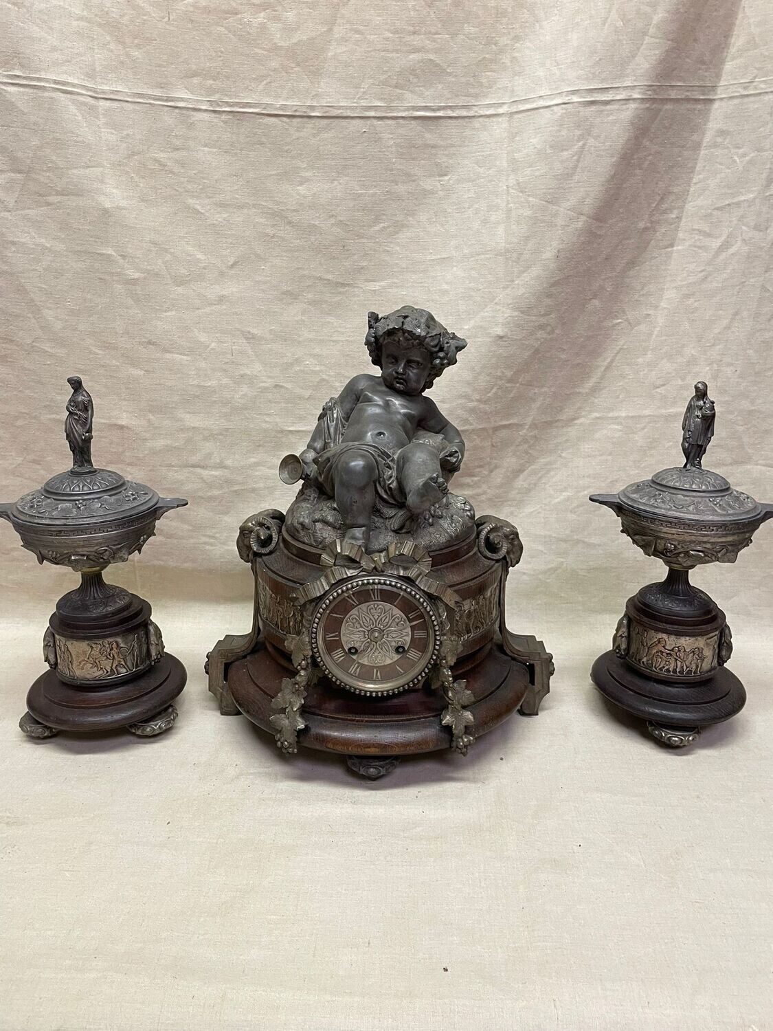 Garniture de cheminée en bois à sujet en régule représentant Bacchus jeune, tête de bélier avec paire de cassolettes à décor de vestales - h : 36 cm