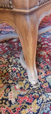 GRAND FAUTEUIL à dossier droit de style Régence en bois naturel mouluré et sculpté de recailles, les pieds galbés réunis par une entretoise en X. 112 x 66 x 62 cm.