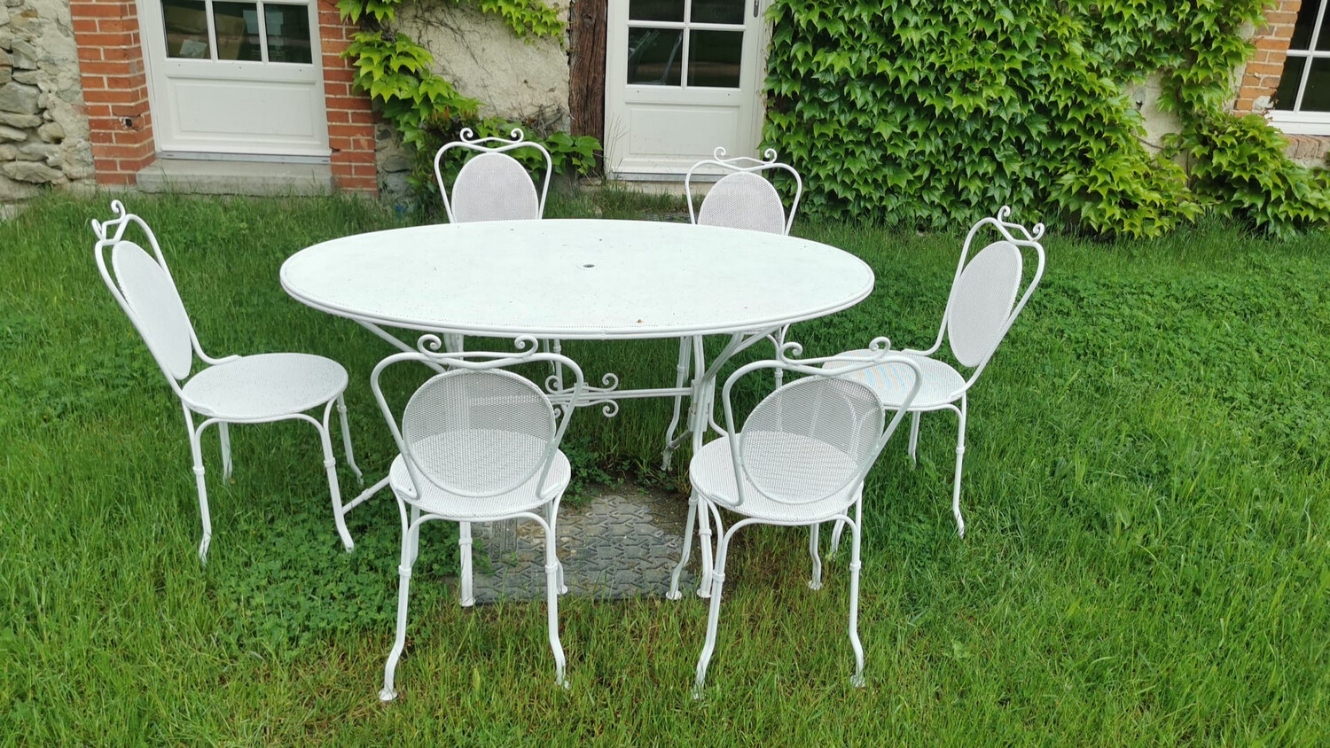 Salon de jardin, en métal rechampi blanc perforé comprenant une table oblongue et six chaises au modèle