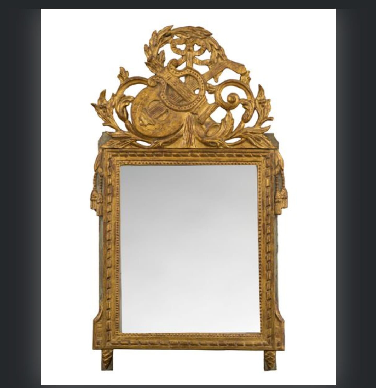 Miroir en bois mouluré, sculpté et doré à décor au sommet d'instruments de musique. XVIllème 102x61 cm.