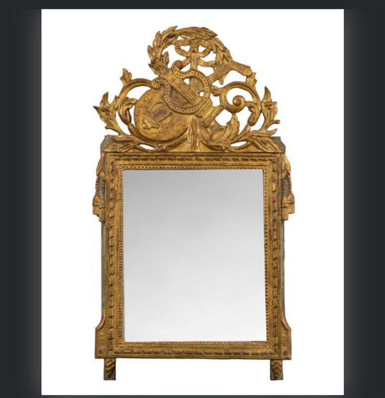 Miroir en bois mouluré, sculpté et doré à décor au sommet d'instruments de musique. XVIllème 102x61 cm.