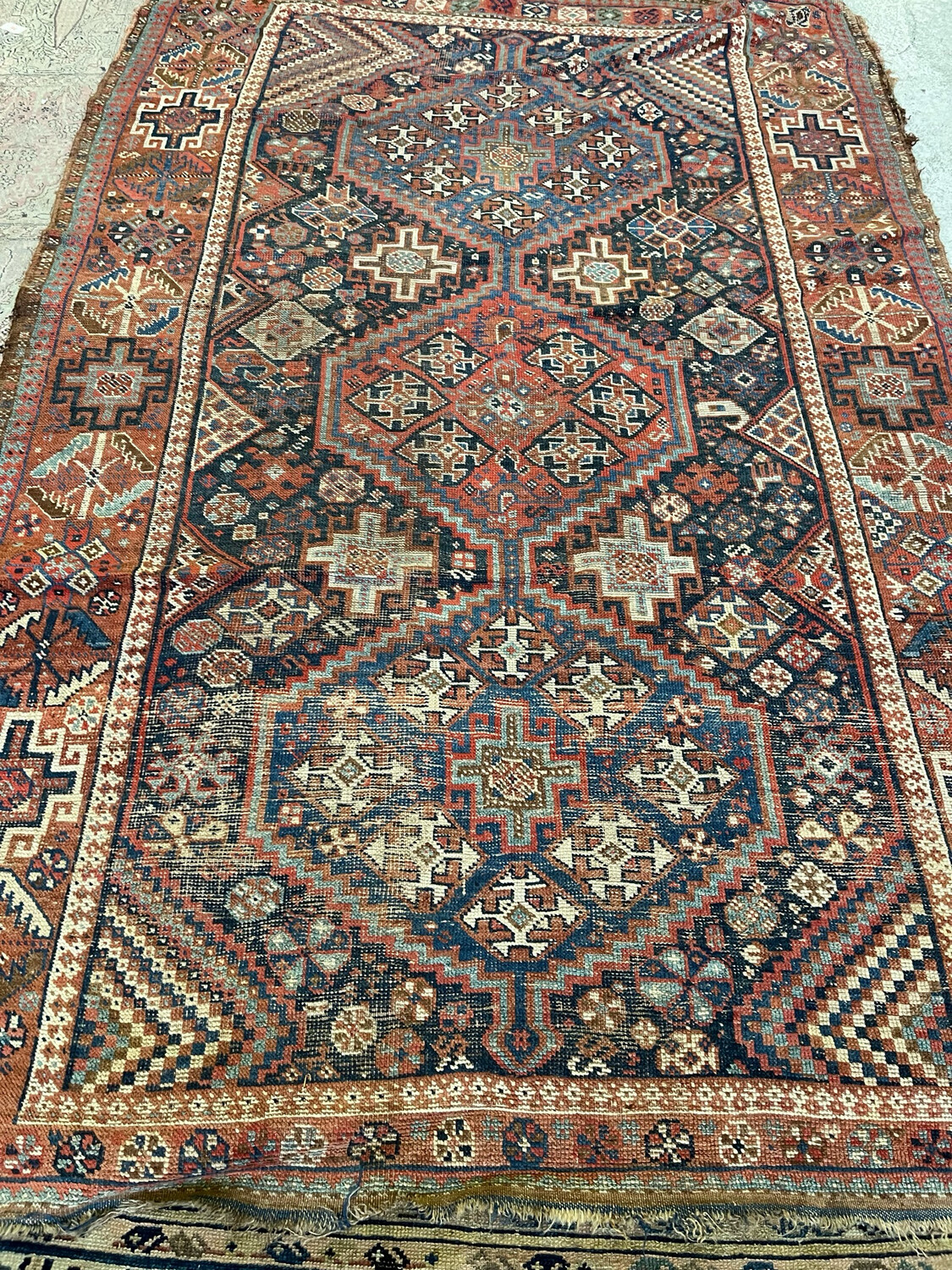 Tapis en laine à décor de motifs géométriques sur fond rouge. 241 x 159 cm.