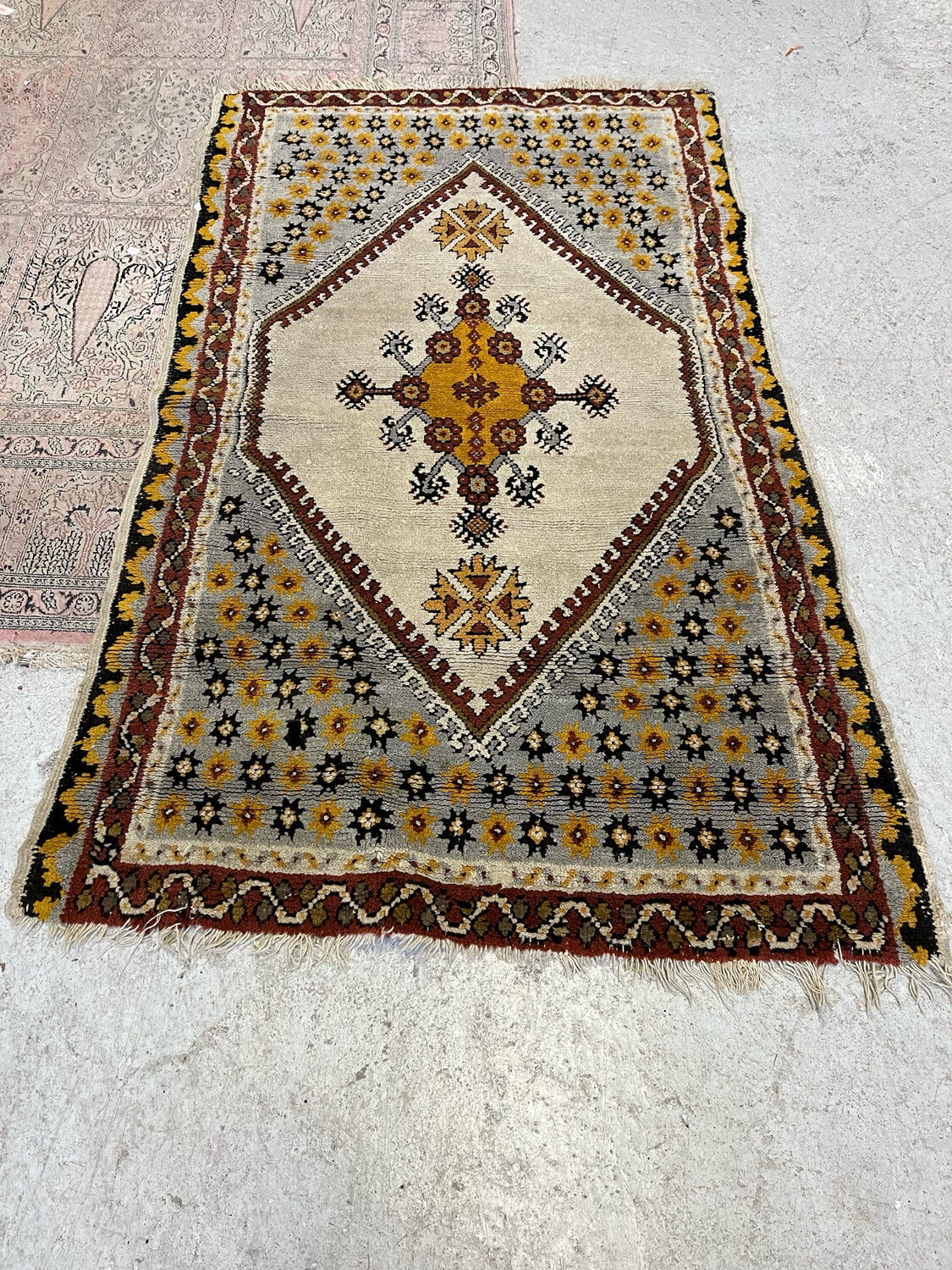 TAPIS en laine à décor de motifs ocres sur fond crème. 180 x 115 cm. Usures d'usage.