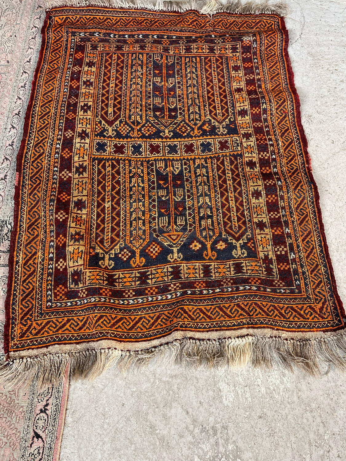 ORIENT. Tapis en laine à décor géométrique polychrome sur fond bordeaux et orange. 136 x 99 cm