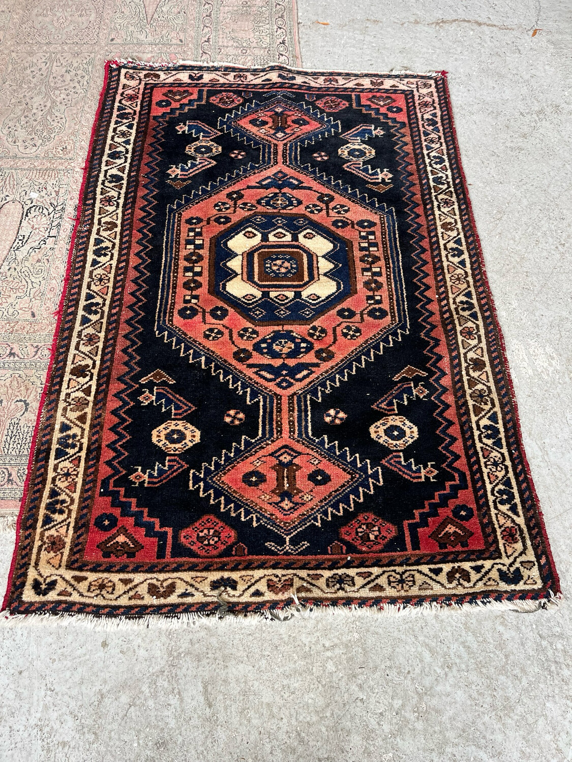 Tapis rectangulaire en laine à décor géométrique dans les teintes, bleue, verte, saumon sur champs bleu marine et bordeaux - 156 x 103 cm