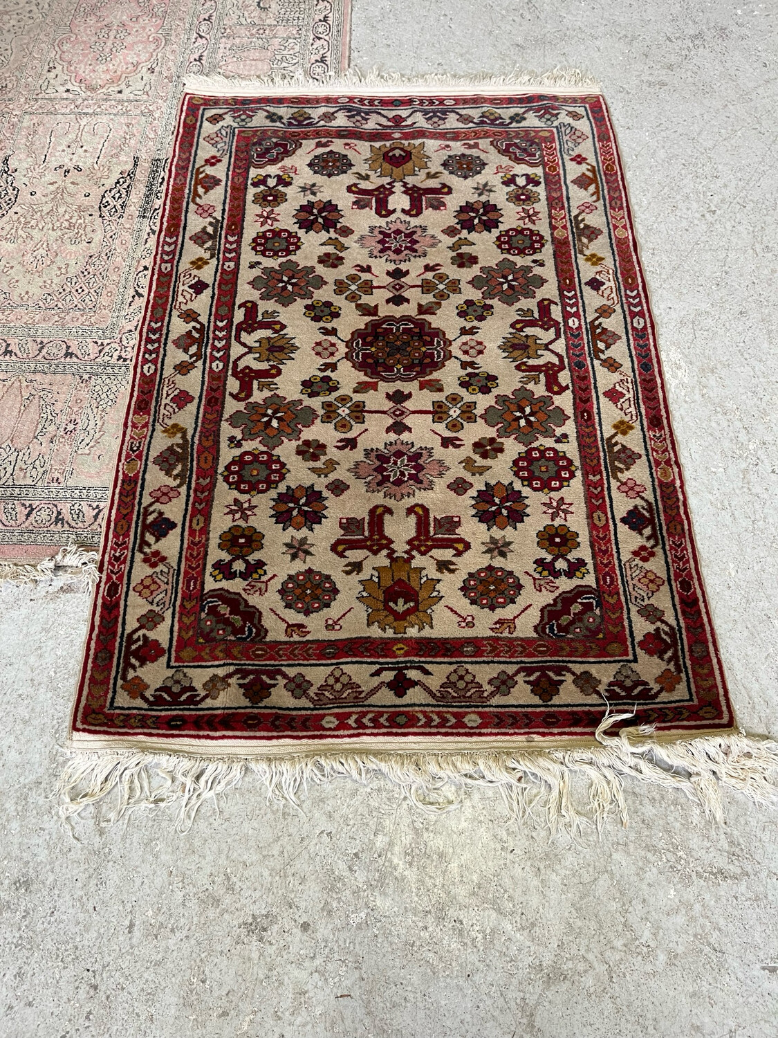 Tapis rectangulaires en laine à décor géométrique et floral stylisé dans les teintes bleu, rouge, vert sur champ beige et rouge - 126 x 82 cm