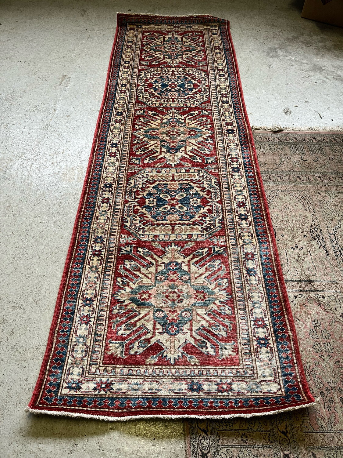 Tapis rectangulaires en laine à décor géométrique et floral stylisé dans les teintes bleu, rouge, vert sur champ beige et rouge - 270 x 84 cm