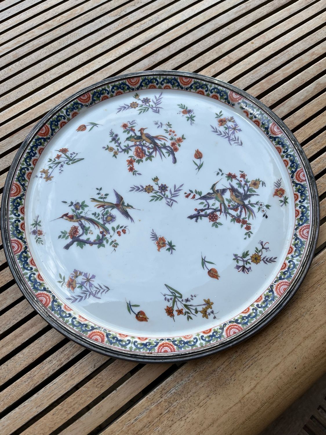 Grande assiette en porcelaine entouré de métal argenté, décor fleurs et oiseaux - D 32 cm