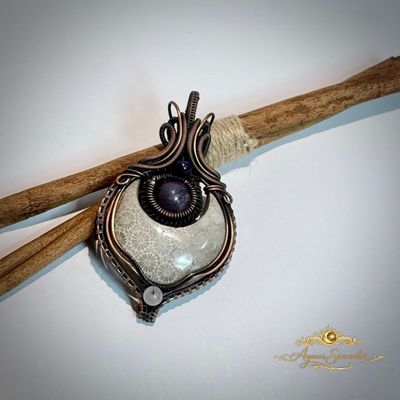     Handgemaakte fossil coral hanger van koper met paarse steen op houten achtergrond