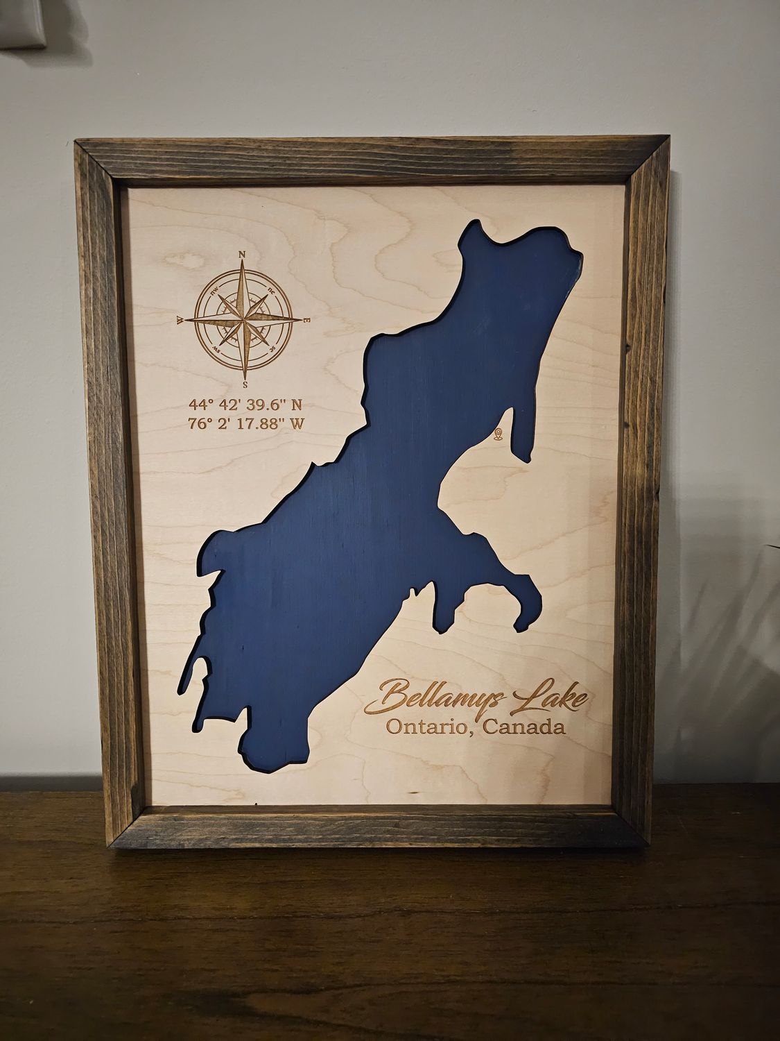 A View of the final product for Bellamys Lake, Ontario Canada. Hand Painted with Navy Blue to represent the body of water, perfectly framed in a rustic pine frame.
