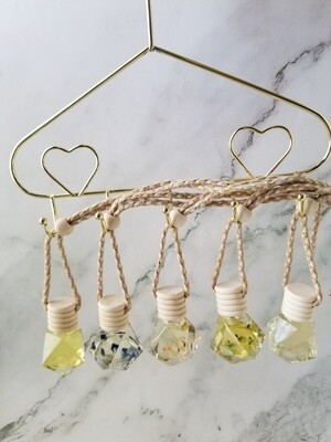 Flower filled car diffuser with gemstone shaped glass bottle, reed diffuser cap, and adjustable rope