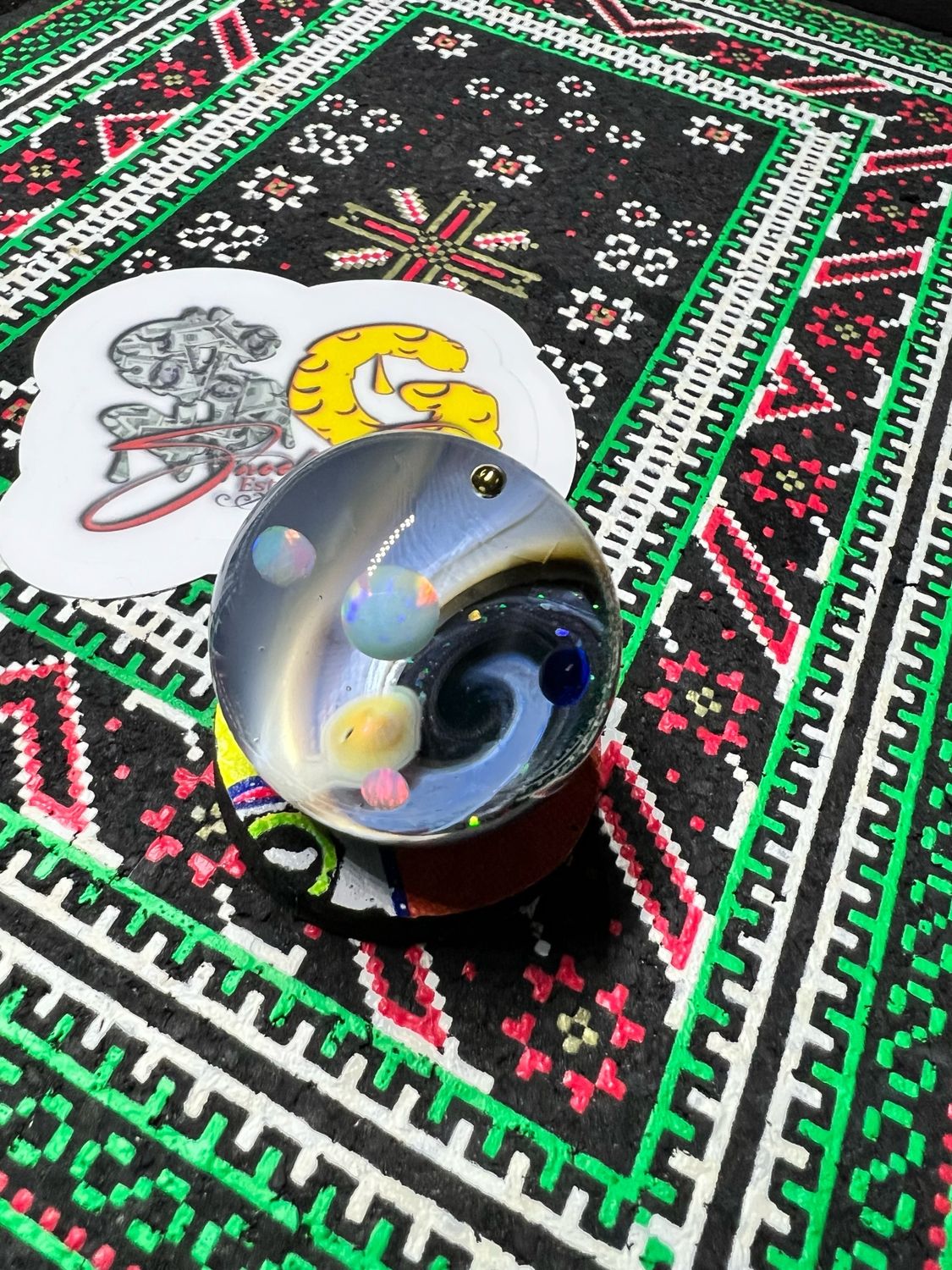 Snook Glass Marble1.35 inch spaced out pocket roller. This one features 6 floating planets. 3 opals,1 pure silver planet🪐,one 24k gold planet and 1 sapphire. Loaded with UV and touch of crushed Opal