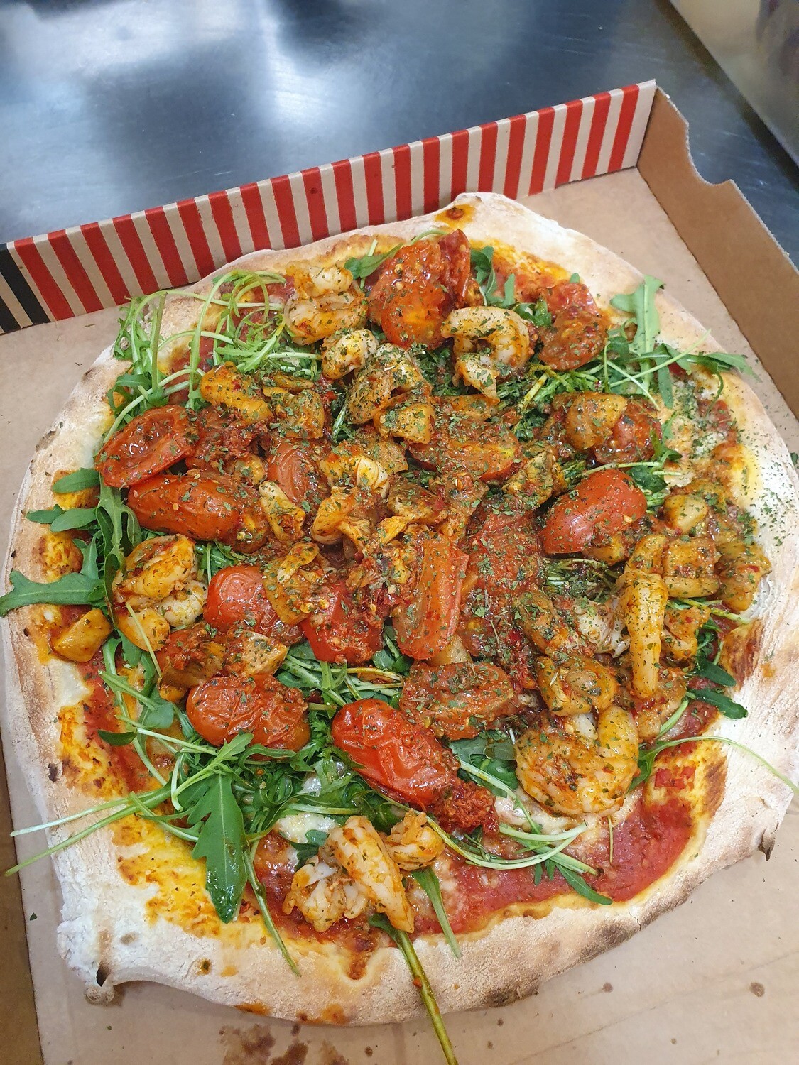 Pizza Karin: sauce tomate, mozzarella, scampi, porcini, tomates cerise, ruccola, nduja