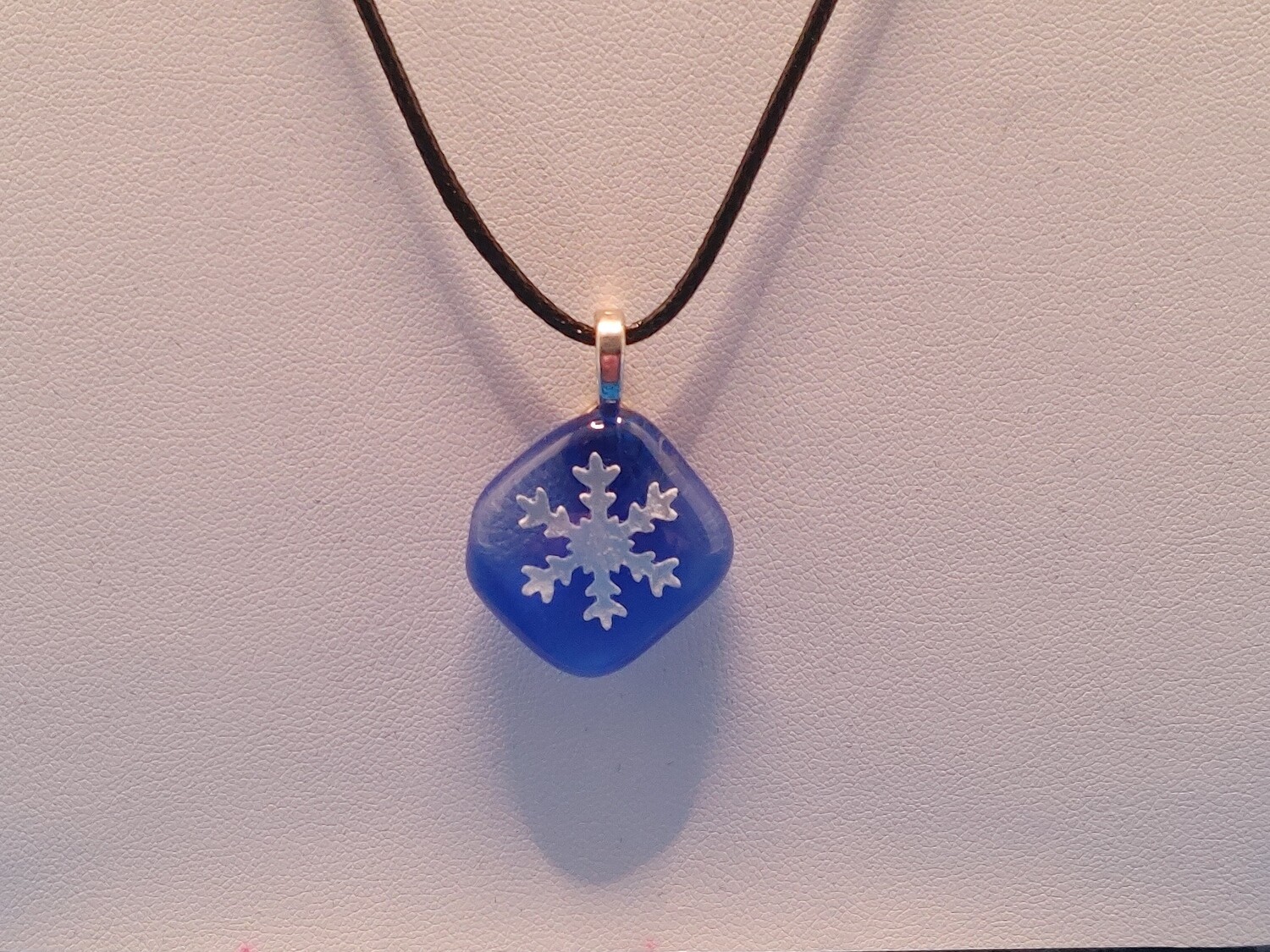 Pressed paper snowflake fused in glass