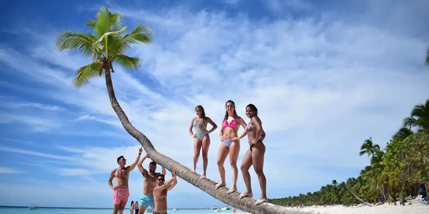 Travelers posing on a tropical palm tree in Saona