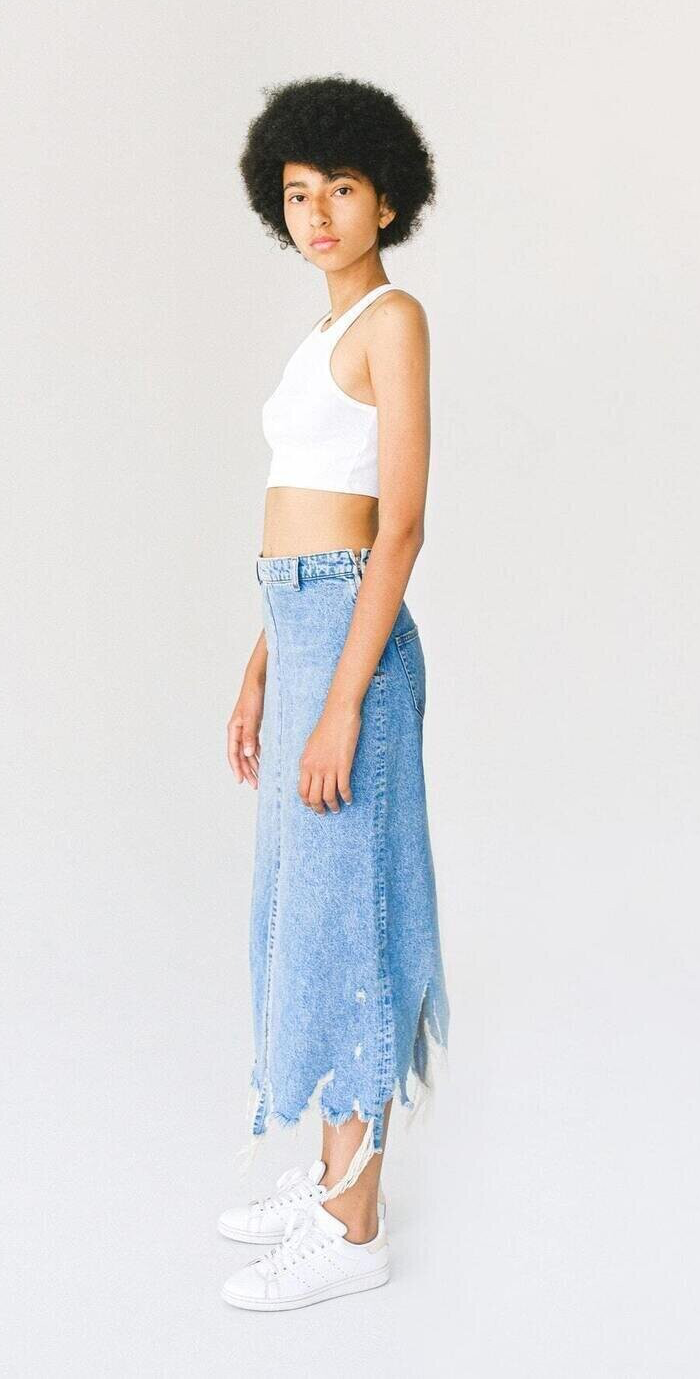 A woman wearing a white top with a blue denim long skirt