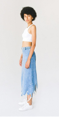 A woman wearing a white top with a blue denim long skirt