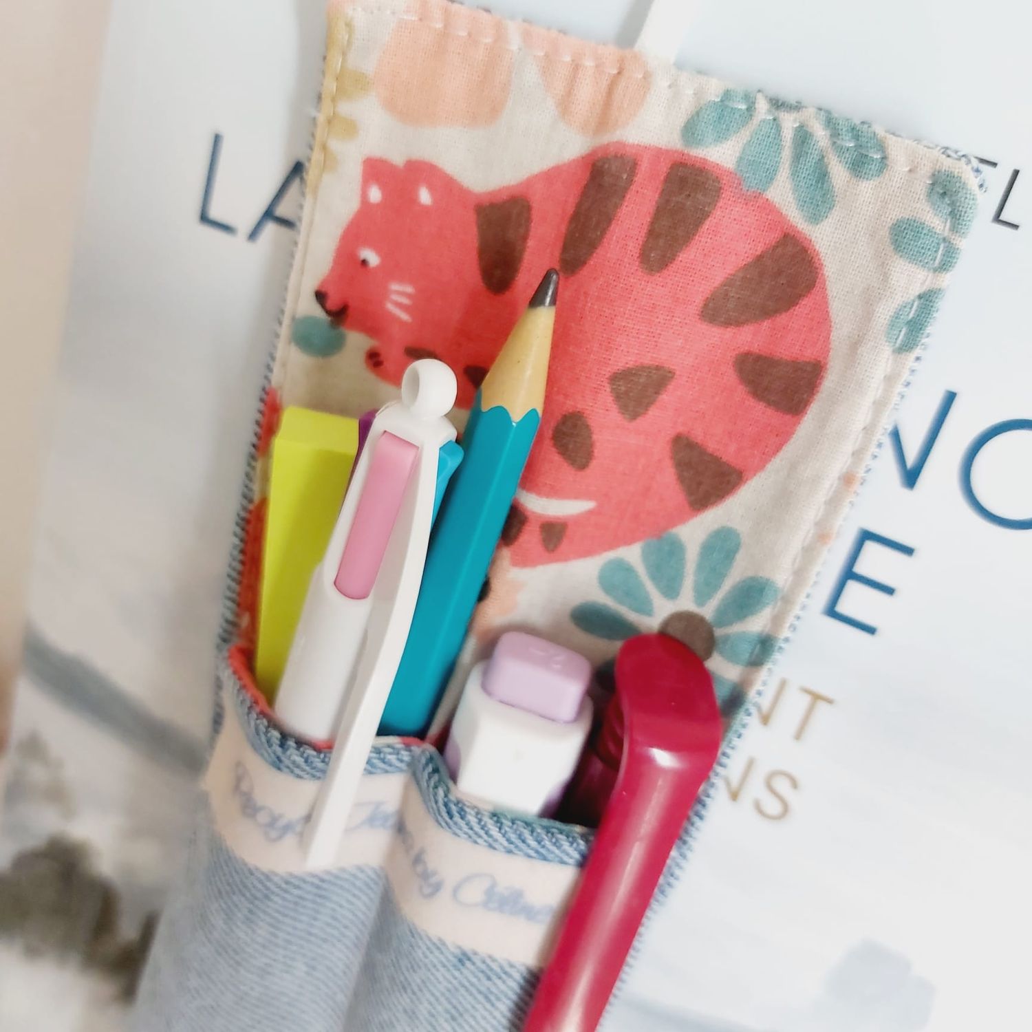 Marque-page Félinéa en jean recyclé et chute de tissu neuf -  inséré dans un livre et garni de stylos - vue rapprochée