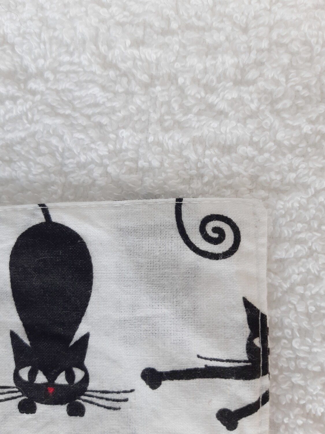 Détail de la couture des serviettes lavables motif chat noir et coeur rouge