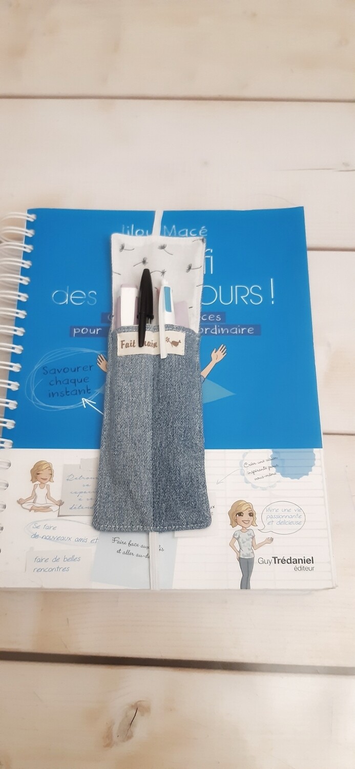 Marque-page Hanu cousu main en jean recyclé et tissu coton, posé sur un livre grand format