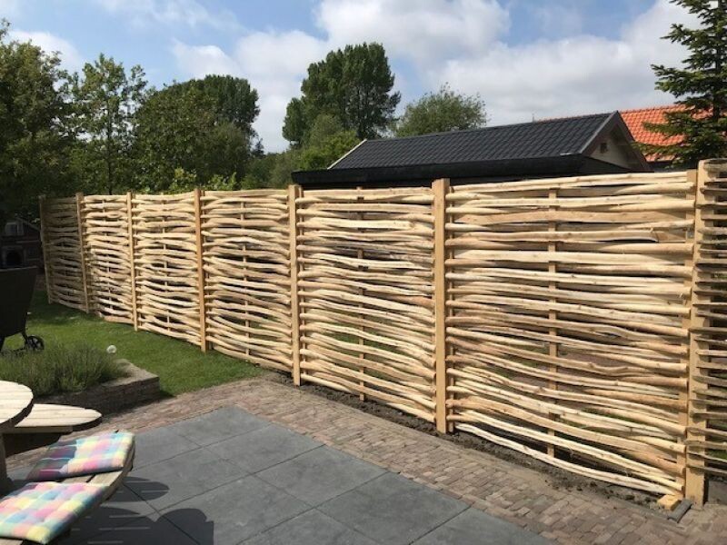 Kastanje vlechtschermen schutting in een tuin.