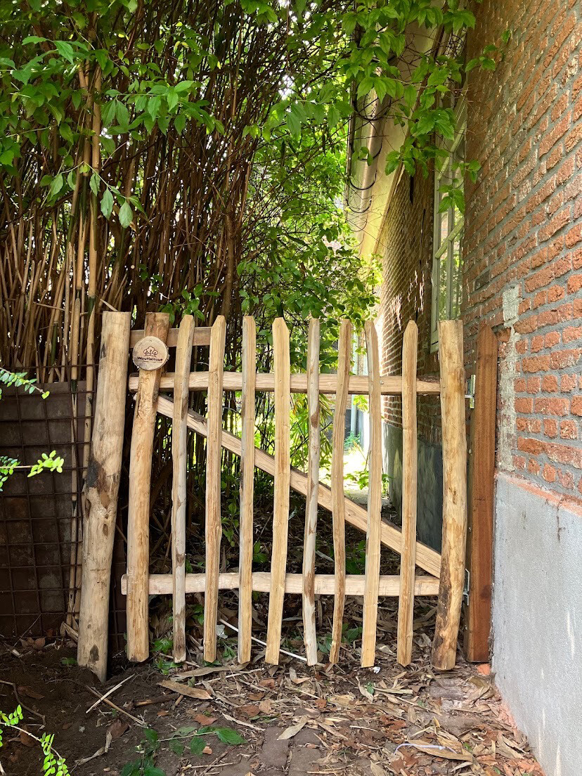 Kastanje tuinpoort tussen een muur en tuin.