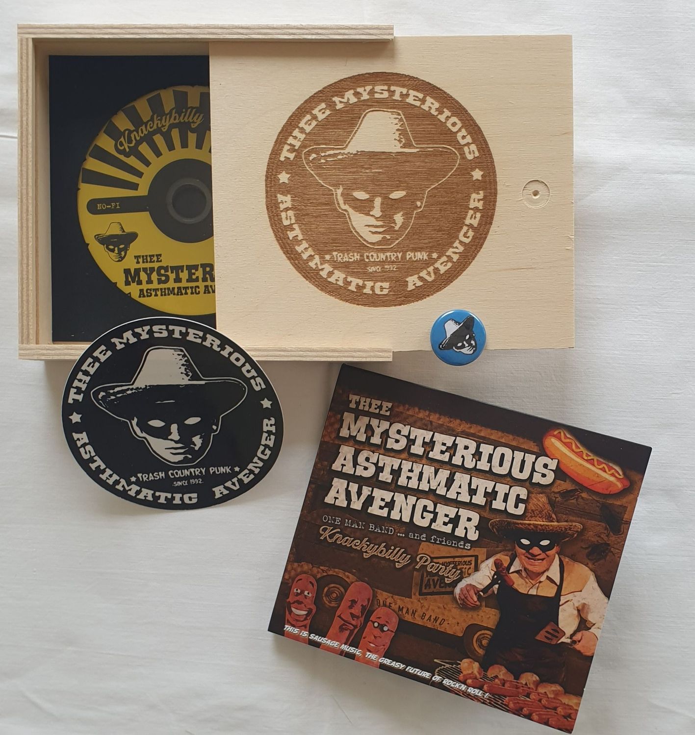 Thee Mysterious Asthmatic Avenger - Knackybilly Party CD Holzbox mit Branding/Lasergravur + Sticker + Fehlpressung der CD + Button (in zufälliger Farbe) Limited to 10 only