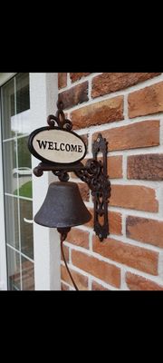 Metalinis varpas su užrašu "Welcome"