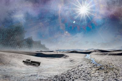 Photo of desert artwork 'Desert Solitaire, depicting a broken down car and a hiker in the distance. Made by Françoise Vaal