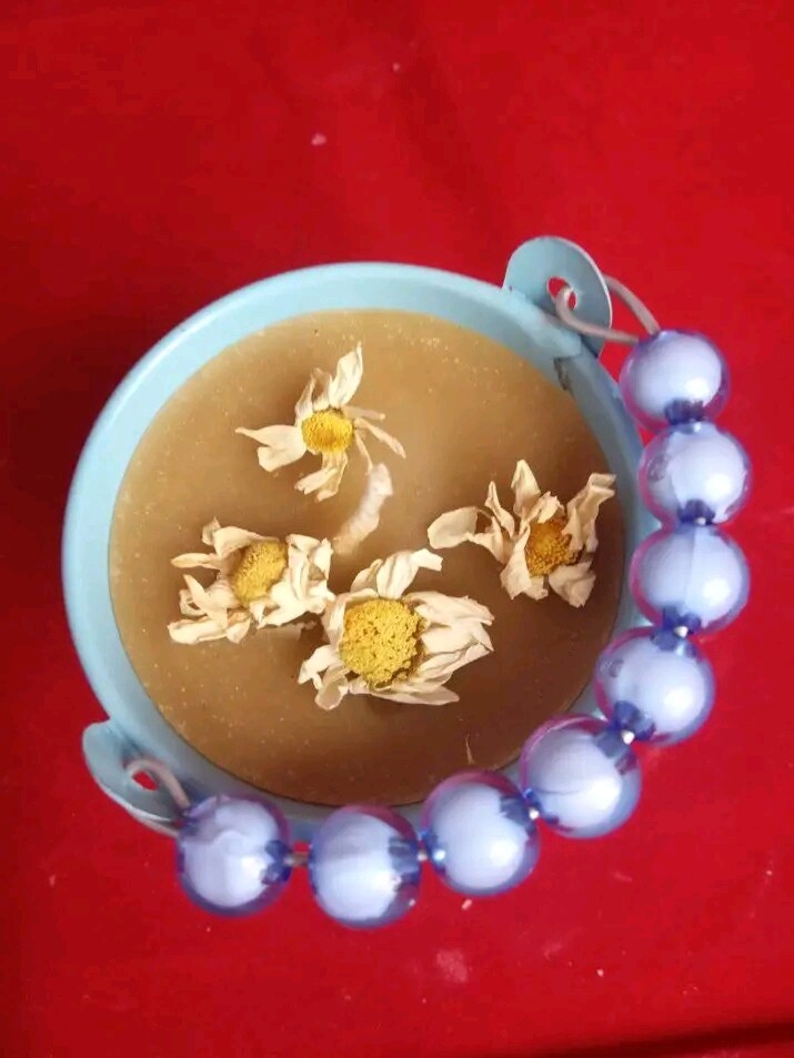 Beeswax candle  in a container with chamomile